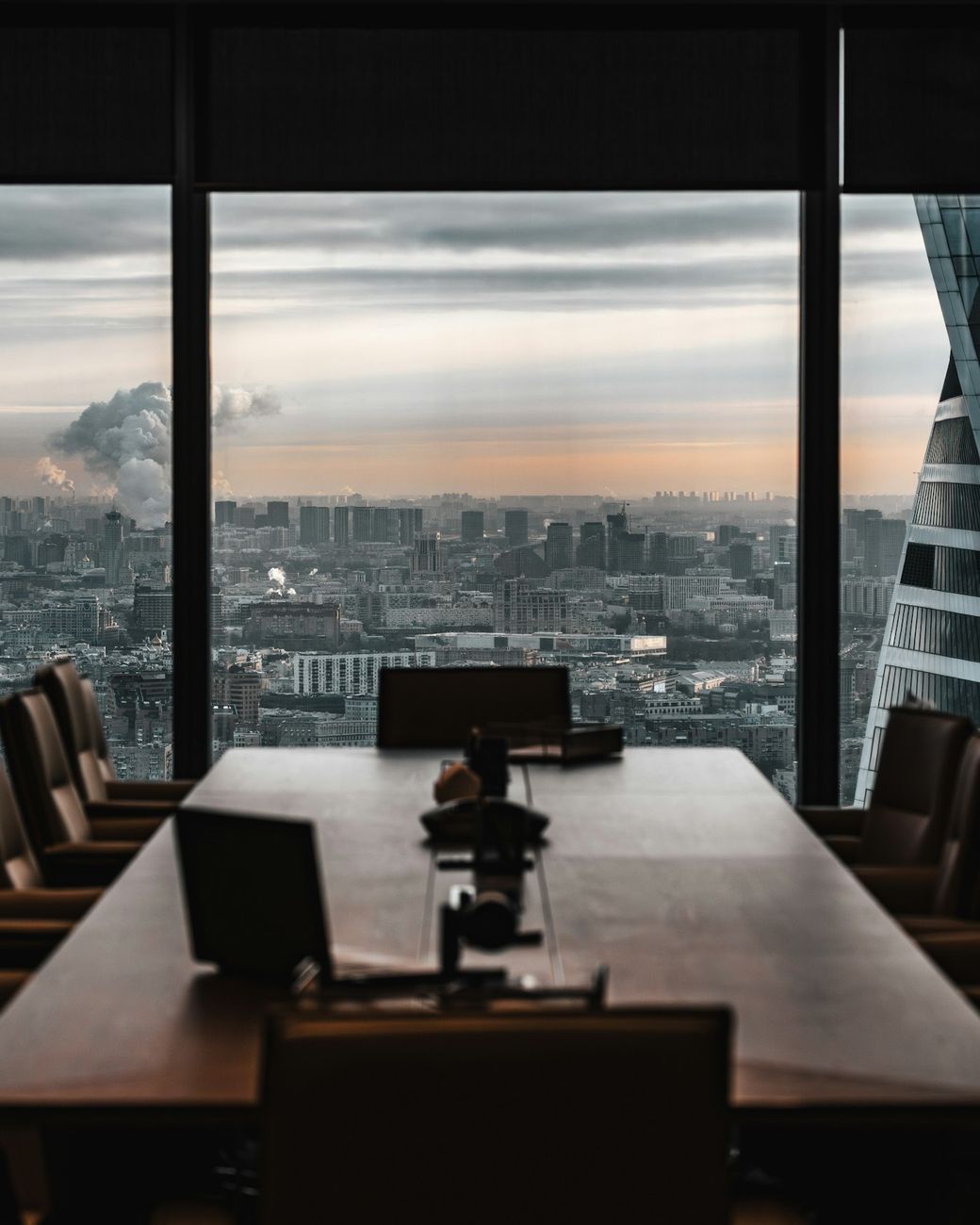 An empty conference room with a panoramic city view at sunset